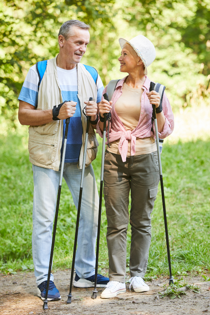 An active senior couple smiling and hiking together outdoors, representing non-surgical joint pain relief solutions from CORE Regenerative Medicine.
