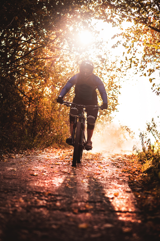mountain biker riding on trail through flowers foreground An active senior couple smiling and hiking together outdoors, representing non-surgical joint pain relief solutions from CORE Regenerative Medicine.